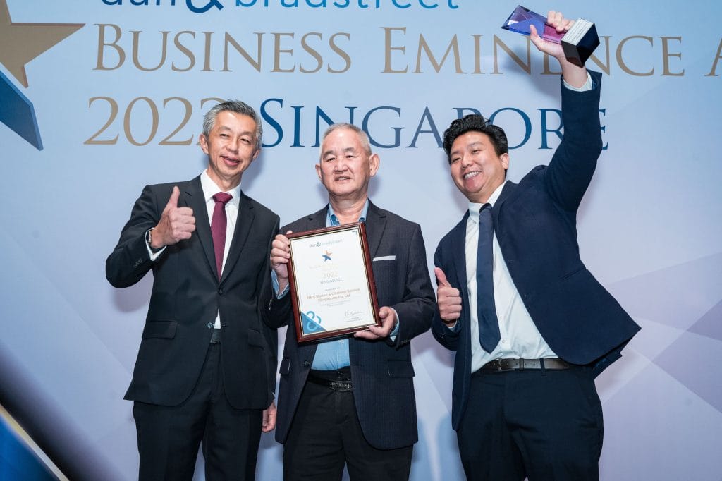 Three men at 2022 Business Eminence Awards ceremony in Singapore. One man holds an award.