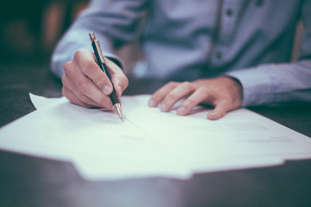 Person signing credit documents with a pen.