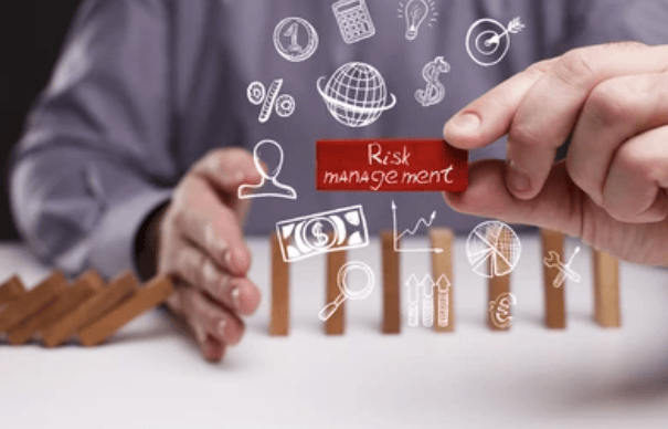 Businessperson holding a "Risk Management" block, surrounded by financial icons.