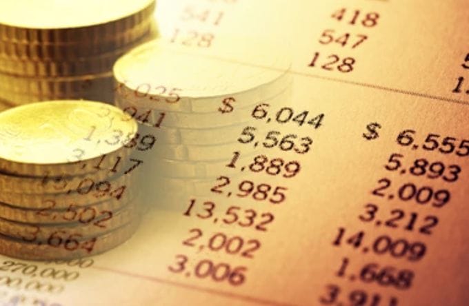 Close-up of coins stacked on financial statement showing numbers.
