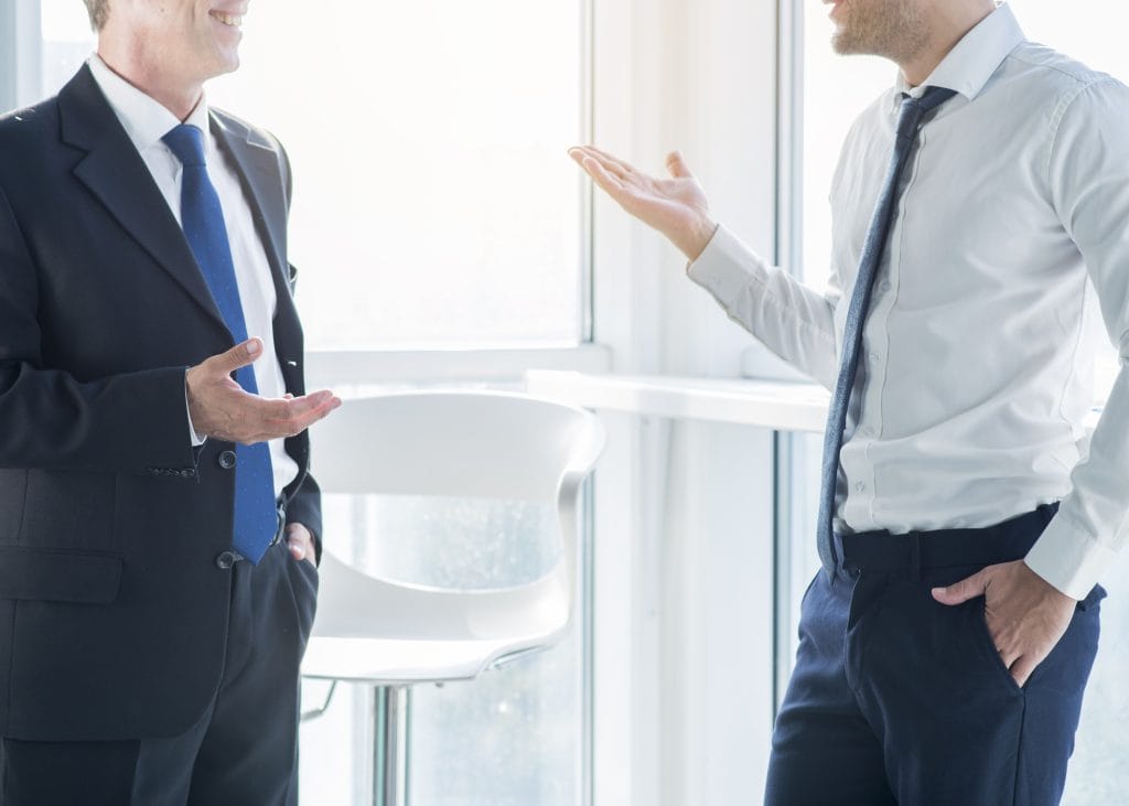 Two businessmen gesturing while having conversation office