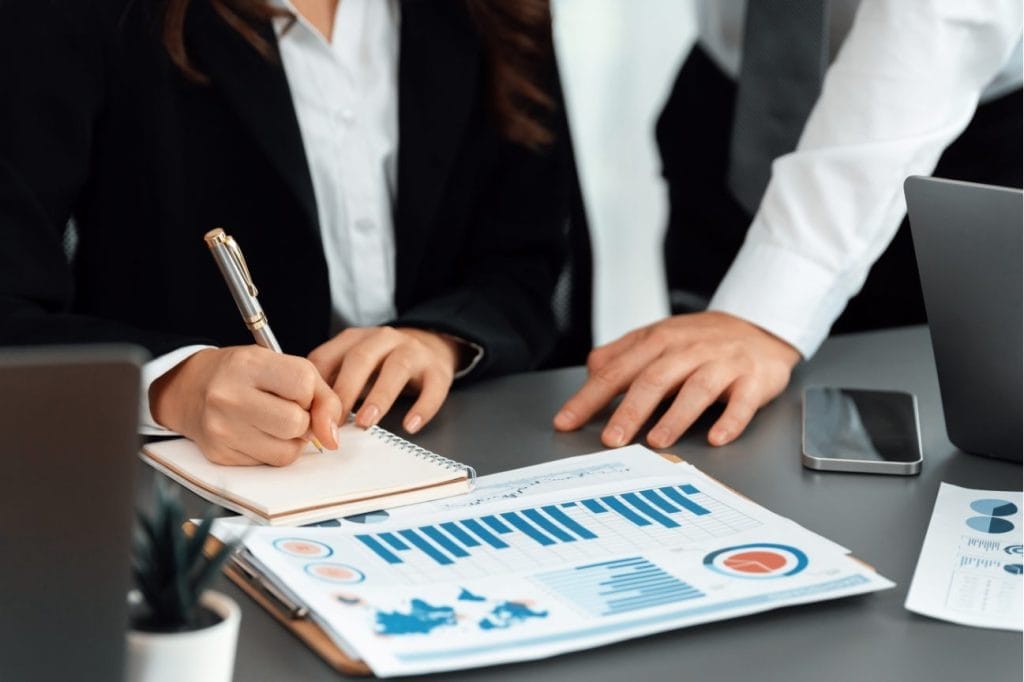 Businesspeople reviewing financial charts and taking notes during a meeting.