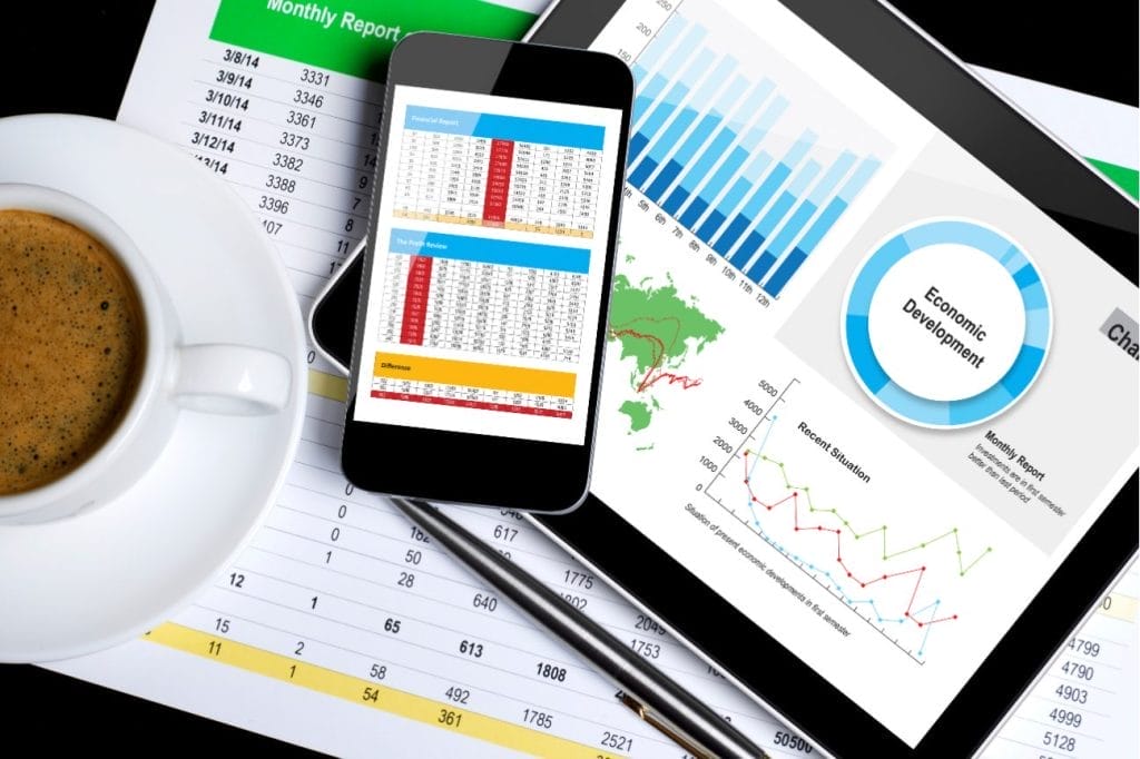 Financial data on tablet and smartphone; charts and graphs show economic development and recent situation.
