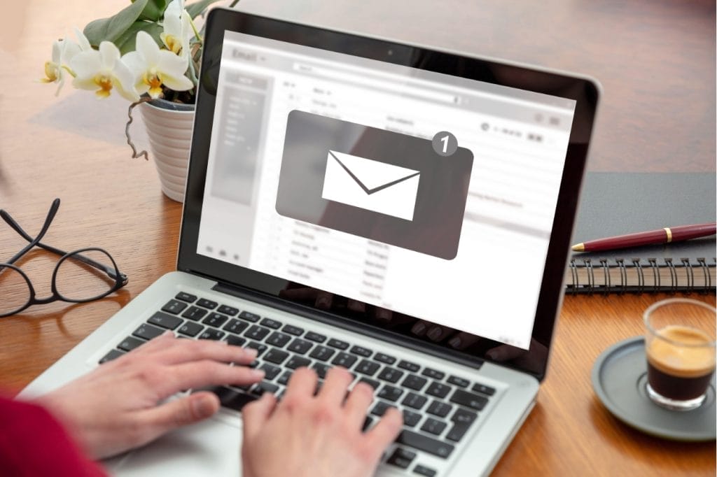 Person checking email on laptop, one new message notification.