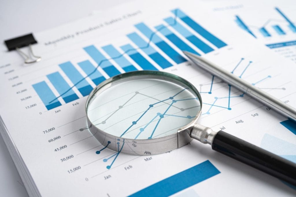Magnifying glass over financial charts and graphs, analyzing data.