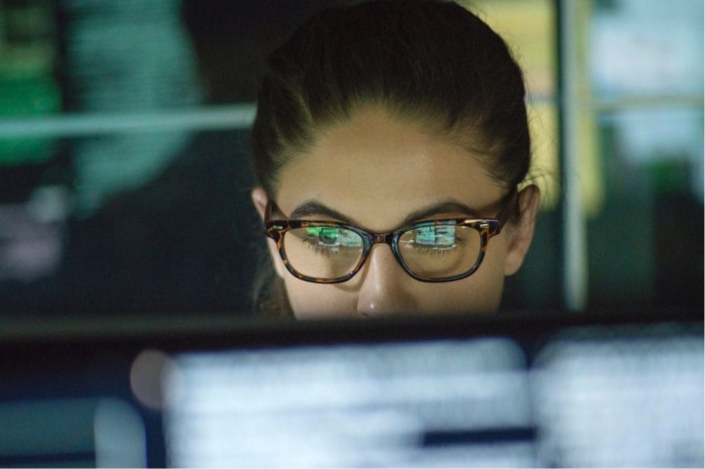 Focused woman in glasses reviewing computer code for online courses.