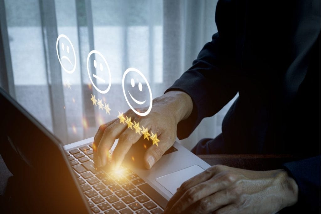 Person using laptop, positive customer feedback shown with stars and smiley faces.