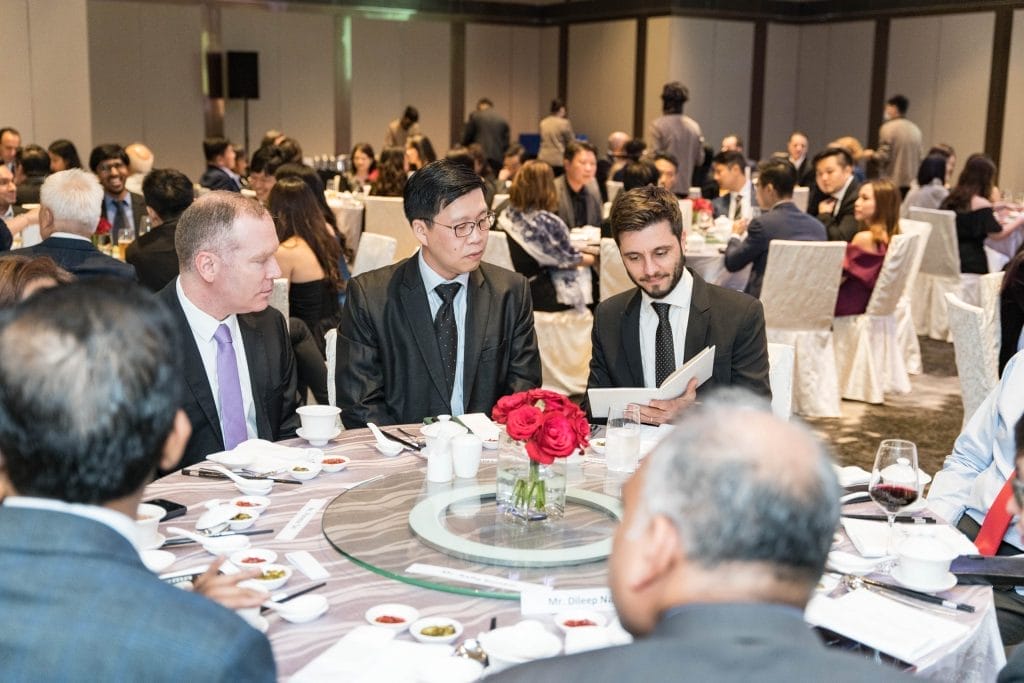 Businessmen at a formal dinner, possibly discussing "Our Story" over wine and roses.